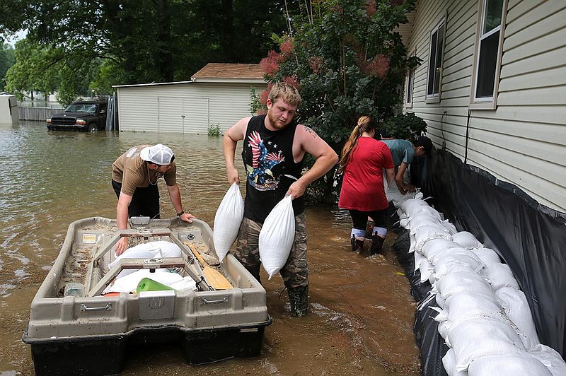 Joseph Shireman pulls a pair of sandbags out of a boat on June 5, 2019, while Gunner Allen (left), Kayla Biggs and Connor Green help put up a wall around Shireman’s home on Lake Conway in Mayflower.
(Arkansas Democrat-Gazette/Thomas Metthe)