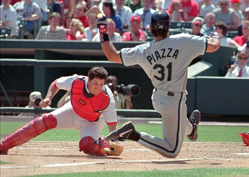 Former St. Louis Cardinals catcher Tom Pagnozzi, here trying to tag out Mike Piazza of the Florida Marlins at the plate during a 1998 game, honed his skills for the position at Arkansas in 1983 under the tutelage of former Razorbacks coach Norm DeBriyn. Pagnozzi played for the Cardinals for 12 seasons from 1987-98, earning Gold Gloves in 1991, 1992 and 1994. (AP file photo) 