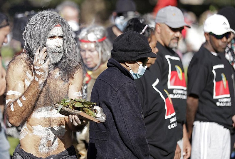 A member of Australia’s indigenous people takes part in a tradi- tional smoking ceremony Sunday at a rally in Sydney. (AP/Rick Rycroft) 
