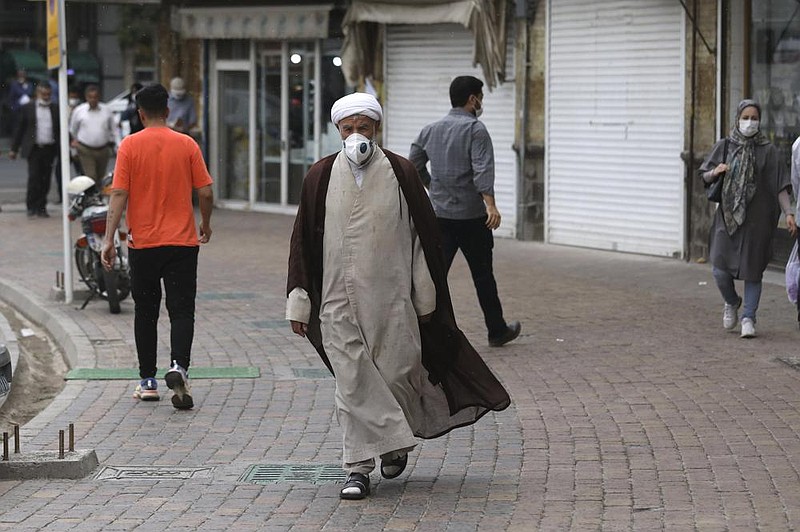 A cleric wears a mask Sunday on a sidewalk in Zanjan, Iran. Before the new mandate, wearing a mask in Iran had been encouraged but was a personal choice. More photos at arkansasonline. com/76iran/ (AP/Vahid Salemi) 
