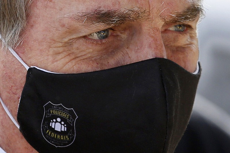 FILE - In this May 26, 2020 file photo, Brazil's President Jair Bolsonaro, wearing a face mask with a logo of the Federal Police, leaves his official residence of Alvorada Palace in Brasilia, Brazil. (AP Photo/Eraldo Peres, FIle)

