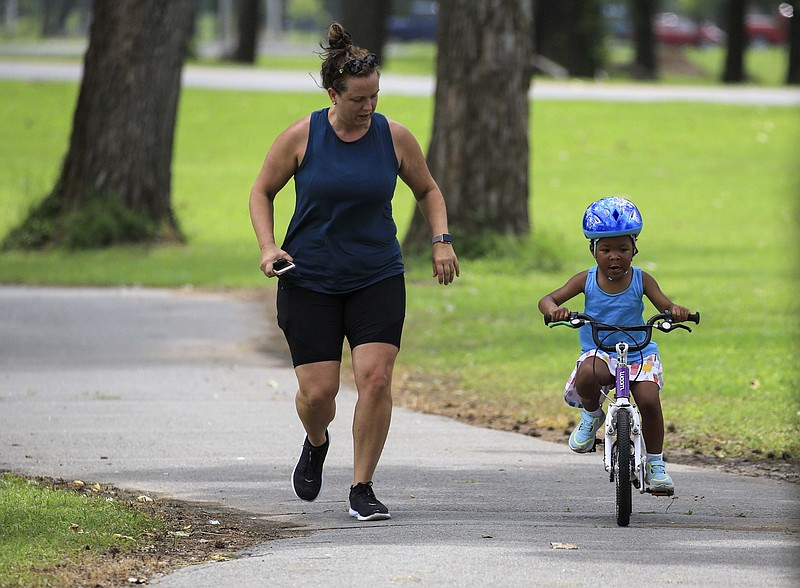 Ryan O'Malley, left, runs along side her daughter, Bailey, 4, as she learns to ride her bike Tuesday June 30, 2020 in North Little Rock's Burns Park. (Arkansas Democrat-Gazette/Staton Breidenthal)