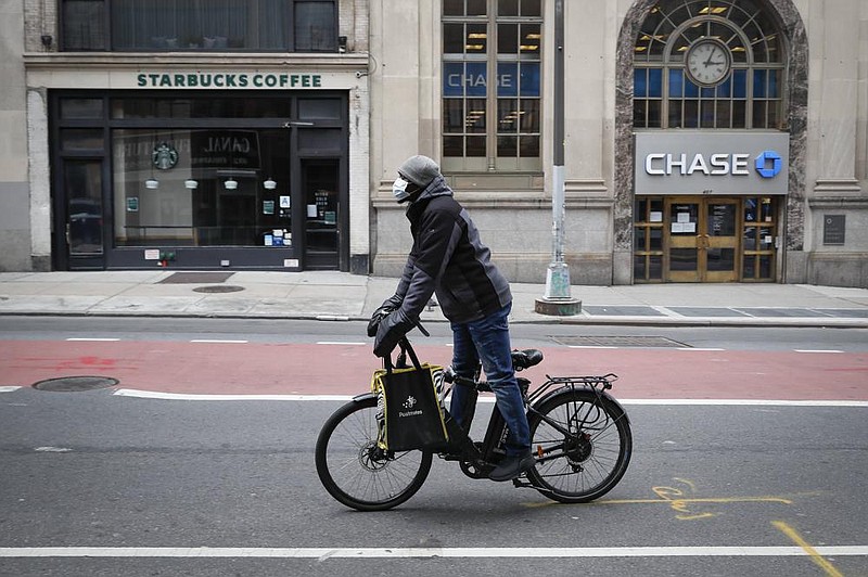 Postmates delivery worker rides down a mostly empty Broadway in April in the Manhattan borough of New York. The pandemic has increased demand for third-party delivery orders while cutting into the ride-hailing businesses of companies such as Uber. (AP) 
