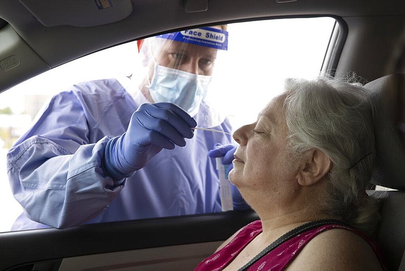 Registered nurse Keith M. takes a sample from Jerri at a drive-thru covid-19 test site at Austin Emergency Center in Austin, Texas, on Wednesday, July 8, 2020. 
(Jay Janne/Austin American-Statesman via AP)