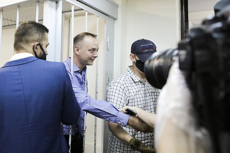 Ivan Safronov, an adviser to the director of Russia’s state space corporation (second from left), greets supporters Tuesday behind bars in a courtroom in Moscow. (AP/Moscow News Agency/Sofia Sandurskaya) 
