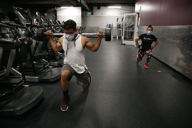 People wear masks while exercising at a gym in Los Angeles in this Friday, June 26, 2020, file photo. On Thursday, July 9, 2020, the World Health Organization acknowledged the possibility that covid-19 might be spread in the air under certain conditions.
