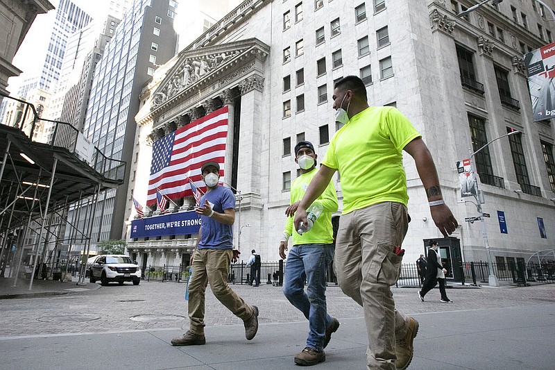 Workers wearing masks walk by the New York Stock Exchange during the coronavirus pandemic, Thursday, July 9, 2020, in New York.