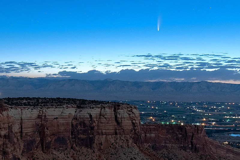 Comet Neowise soars in the horizon of the early morning sky in this view from the near the grand view lookout at the Colorado National Monument west of Grand Junction, Colo., Thursday, July 9, 2020. The newly discovered comet is streaking past Earth, providing a celestial nighttime show after buzzing the sun and expanding its tail. (Conrad Earnest via AP)

