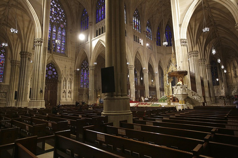 FILE - In this Sunday, April 12, 2020 file photo, Cardinal Timothy Dolan, right, delivers his homily over mostly empty pews as he leads an Easter Mass at St. Patrick's Cathedral in New York.