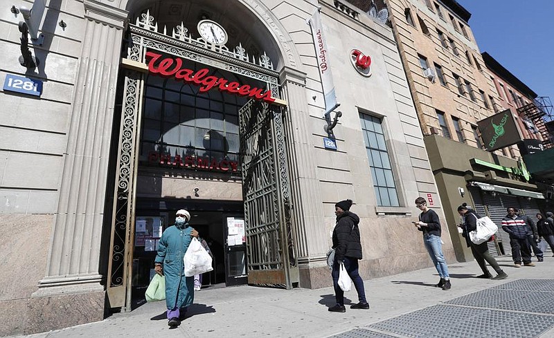 A woman leaves a Walgreens pharmacy in New York in March as customers line up on the sidewalk outside. The pandemic has severely curbed sales at the drugstore chain.
(AP/Kathy Willens)