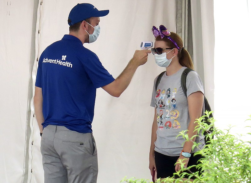 A guests gets her temperature taken before entering the official reopening day of the Magic Kingdom at Walt Disney World in Lake Buena Vista, Fla., Saturday, July 11, 2020. Disney reopened two Florida parks, the Magic Kingdom and Animal Kingdom, Saturday with limited capacity and safety protocols in place in response to the coronavirus pandemic. (Joe Burbank/Orlando Sentinel via AP)