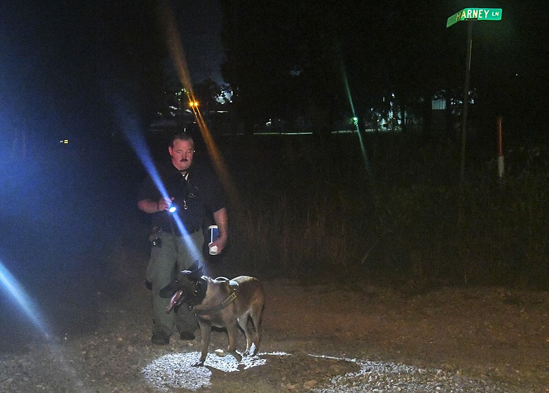 A Garland County sheriff's deputy and a K-9 search the area of Akers Road and Marney Lane around midnight Saturday following a double homicide at a nearby apartment complex at around 6:30 p.m. - Photo by Grace Brown of The Sentinel-Record