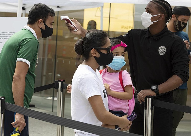 A customer gets a temperature check Saturday before entering an Apple Store in Boston. (AP/Michael Dwyer) 
