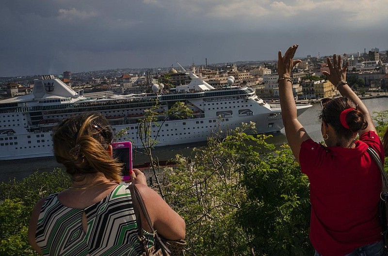 A woman waves goodbye as another takes pictures of the Em- press of the Seas, a Royal Caribbean vessel, as it navigates out of the harbor in Havana, Cuba, in June, 2019. Royal Caribbean and Norwegian Cruise Line Holdings have organized a panel of health experts to create a plan to return to operation by the end of August. 
(AP/Ramon Espinosa) 