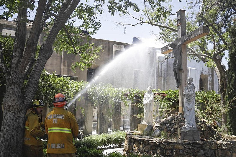 Firefighters hose down hot spots Saturday at the San Gabriel Mission in California. (AP/Marcio Jose Sanchez) 