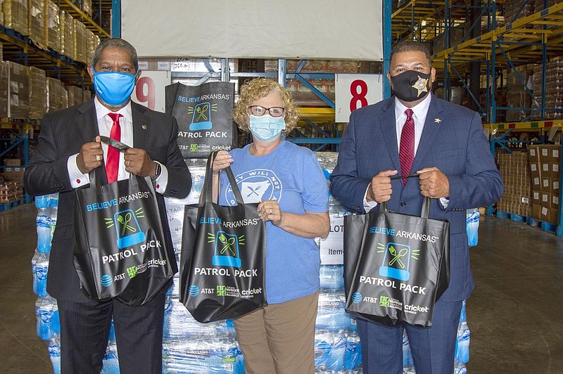 AT&T Arkansas president Ronnie Dedman, Arkansas Foodbank CEO Rhonda Sanders and Pulaski County Sheriff Eric Higgins show shopping bags filled with food that police officers can distribute to families in emergency situations.
(Arkansas Democrat-Gazette/Cary Jenkins)