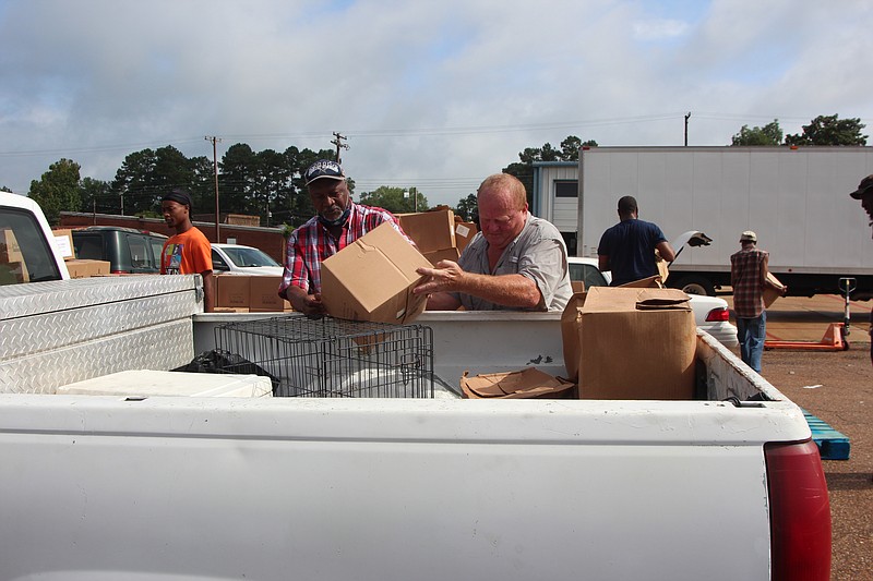 Waldo Mayor Kenneth Haupt (right) and another volunteer load boxes into a pickup truck during a Harvest Food Center distribution last week. The mayor said residents started lining up four hours before the giveaway.