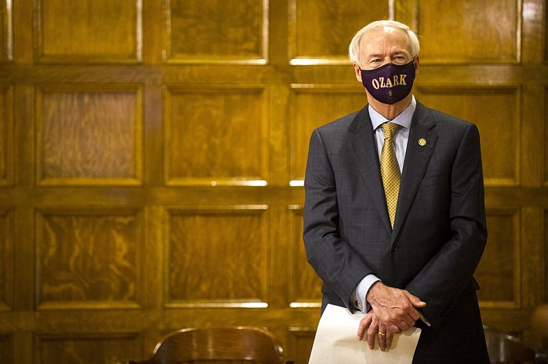 Gov. Asa Hutchinson wears a mask given to him by the Ozark Hillbillies Golf Team as he waits to speak at his daily briefing Tuesday. More photos at arkansasonline. com/715gov/. 
(Arkansas Democrat-Gazette/ Stephen Swofford) 
