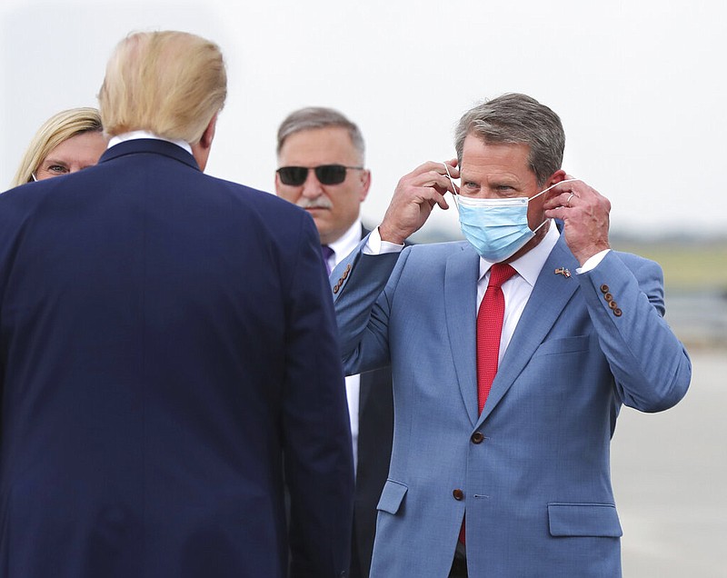 Georgia Gov. Brian Kemp adjusts his mask as he greets President Donald Trump during the president's Georgia visit at the UPS Hapeville hub at Hartsfield-Jackson International Airport in Atlanta on Wednesday, July 15, 2020.