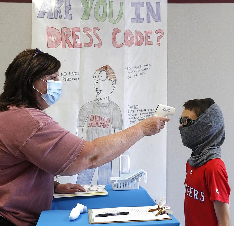 Science teacher Ann Darby checks sixth grader Anthony Gonzales’ temperature Tuesday before letting him enter a summer science and technology camp at Wylie High School in Wylie, Texas. More photos at arkansasonline.com/715covid/. (AP/LM Otero) 