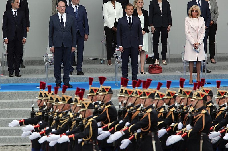 French Prime Minister Jean Castex (front from left), President Emmanuel Macron and wife Brigitte Macron watch the Bastille Day military parade Tuesday in Paris.More photos at arkansasonline.com/715france/. (AP/Francois Mori) 