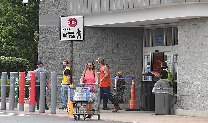 Customers, most wearing masks, enter and exit a Walmart Supercenter in Fayetteville on Wednesday. Starting Monday, all Walmart stores will have health ambassadors stationed at the doors to make sure shoppers wear masks.
(NWA Democrat-Gazette/J.T. Wampler)