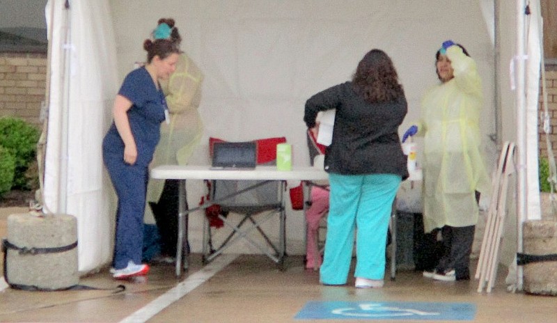 Medical workers set up a tent around the Community Clinic covid-19 evaluation and testing site in Siloam Springs during rainy weather in this March 2020 file photo. Community Clinic had opened four covid-19 testing sites in Northwest Arkansas, including the location outside the Siloam Springs clinic at 500 S. Mount Olive St. 