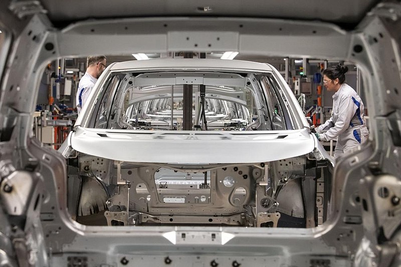 In this February photo, workers complete an electric car ID.3 body at the assembly line during a press tour at the plant of the German manufacturer Volkswagen AG (VW) in Zwickau, Germany. (AP/Jens Meyer) 
