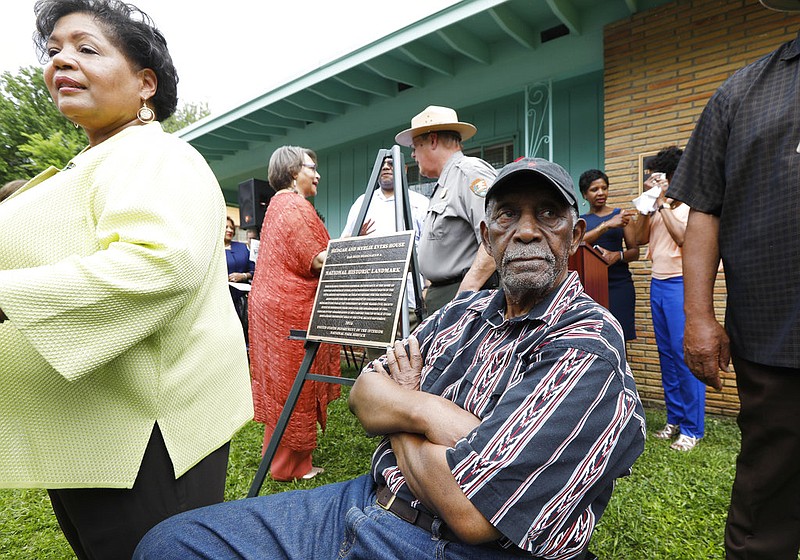 Charles Evers (seated) watches as people mill around the front yard of the Jackson, Miss., home of his brother, the late civil-rights leader Medgar Evers, in this May 24, 2018, file photo. The National Park Service had just unveiled a bronze plaque showing that the home is a national historic landmark. Charles Evers, whose political career included leading the Mississippi NAACP and serving as the state's first Black mayor of a multiracial town since Reconstruction, died Wednesday, July 22, 2020. He was 97.
