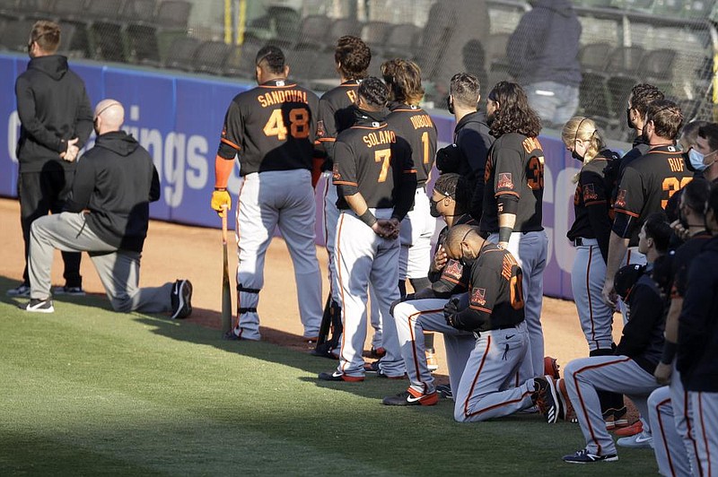Jaylin Davis and Antoan Richardson (lower right) of the San Francisco Giants kneel during the national anthem before an exhibition game against the Oakland Athletics on Monday in Oakland, Calif. Davis said he and his teammates discussed the move before summer camp started. “We wanted it known that we wren’t going to let everything be pushed aside just because baseball is back,” Davis said. 
(AP/Ben Margot) 