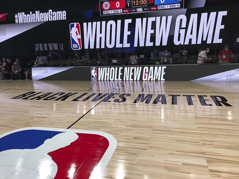 An NBA court at Walt Disney World in Kissimmee, Fla., displays the league’s marketing motto for the restart of the season, “Whole New Game,” along with “Black Lives Matter” across the midcourt line. Play is scheduled to restart July 30. (AP/Tim Reynolds) 