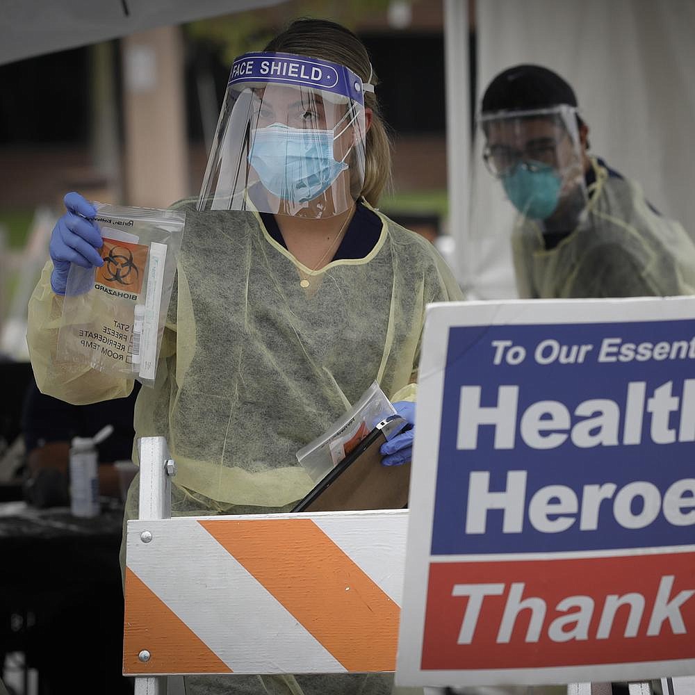 A health worker hands out coronavirus testing kits Wednesday at a mobile site at the Charles Drew University of Medicine and Science in Los Angeles. With a robust testing effort, California’s confirmed coronavirus cases have passed New York’s as highest in the nation. More photos at arkansasonline.com/723virus/.
(AP/Marcio Jose Sanchez)