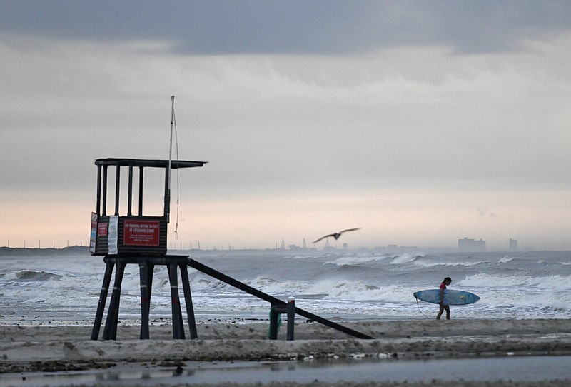 A surfer walks on the beach at J.P. Luby Park in Corpus Christi, Texas, on Friday, July 24, 2020, ahead of Tropical Storm Hanna. The storm is expected to make landfall on Saturday.