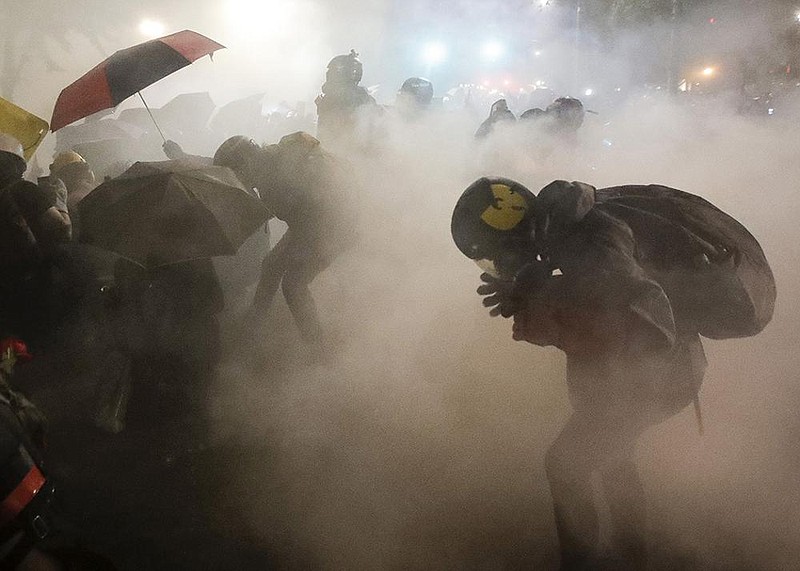 Federal officers launch tear gas Sunday at a group of demonstra- tors during a Black Lives Matter protest at the Mark O. Hatfield United States Courthouse in Portland, Ore. More photos at arkan- sasonline.com/727portland/. 
(AP/Marcio Jose Sanchez) 
