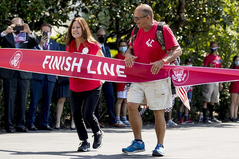 Terry Sharpe, known as the “Walking Marine,” is accompanied by Karen Pence, the wife of Vice President Mike Pence, as he arrives Monday at the White House. (AP Photo/Andrew Harnik) 