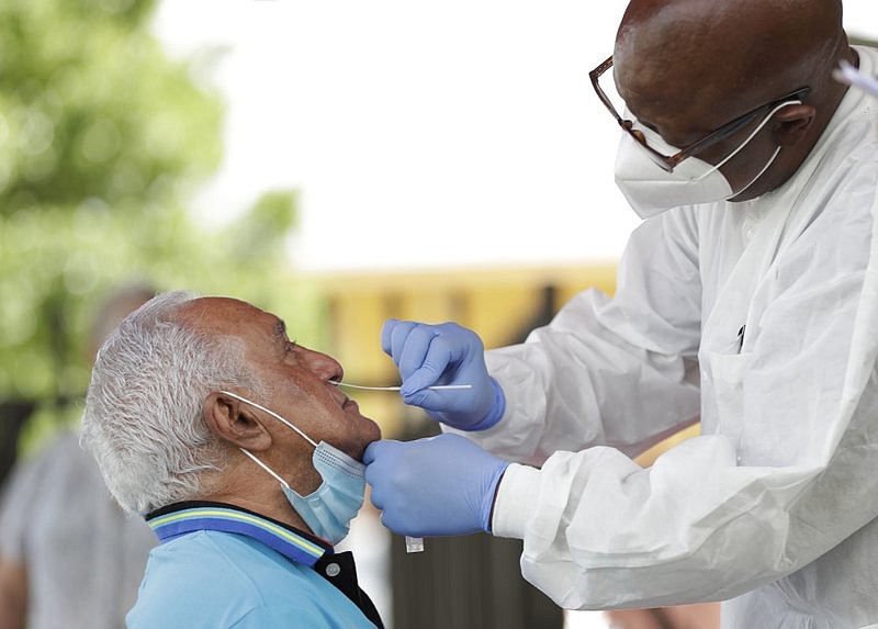 Lab technician James Donald, right, uses a nasal swab to test Hugo Marti for COVID-19 on Tuesday at the AHEPA Apartments in Miami. Miami-Dade County Commissioner Esteban "Steve" Bono and Prime Care Family Medical Centers opened the free testing site to test the residents of the senior apartments.