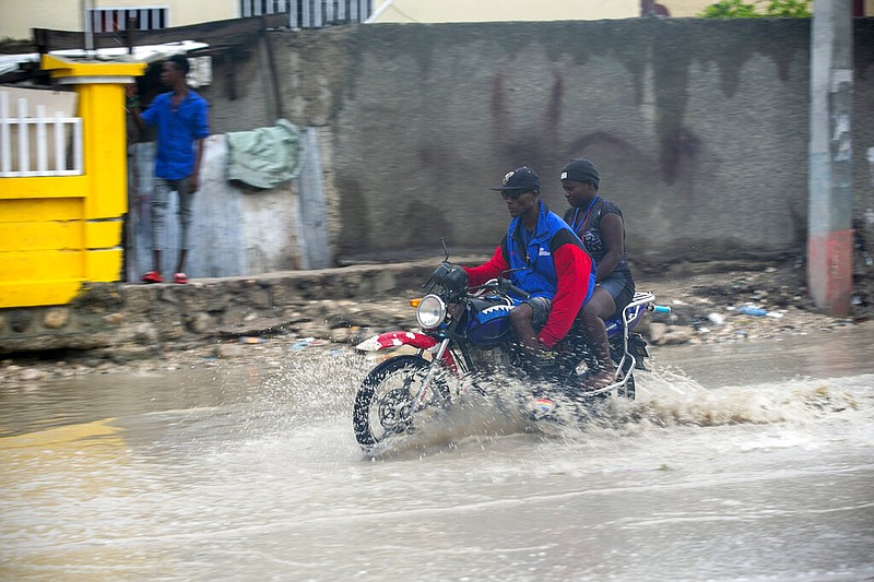 A moto-taxi driver moves through a street flooded by rain brought by the outer bands of Hurricane Isaias, in the Tabarre district of Port-au-Prince, Haiti, early Friday, July 31, 2020. Isaias kept on a path early Friday toward the U.S. East Coast as it approached the Bahamas.