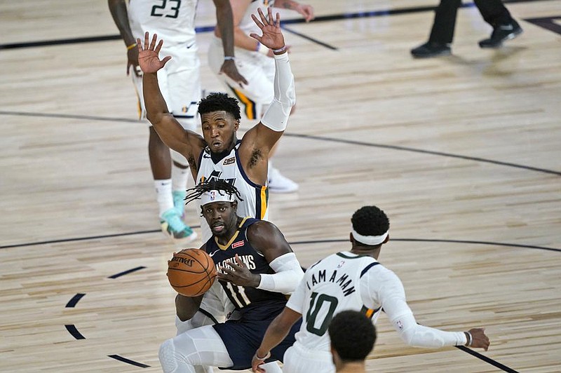 Jrue Holiday (bottom) of the New Orleans Pelicans looks to pass while being defended by Donovan Mitchell of the Utah Jazz on Thursday night at Lake Buena Vista, Fla., during the first game of the NBA’s return from its coronavirus shutdown.
(AP/Ashley Landis)