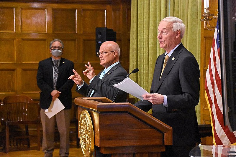 Governor Asa Hutchinson speaks during a COVID-19 briefing on Thursday, July 30 at the state Capitol in Little Rock. Interim ADH Secretary Dr. Jose Romero, left, can be seen, along with Eddie Schmeckenbecher, middle, the governor’s sign language interpreter. (Arkansas Democrat-Gazette/Staci Vandagriff)