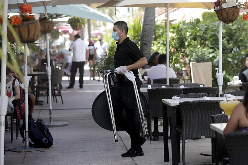 A waiter in protective gear works last month at a restaurant in Miami Beach, Fla. Income for U.S. workers fell 1.1% in June, as the coronavirus recession took a toll on businesses and employees.
(AP/Lynne Sladky)