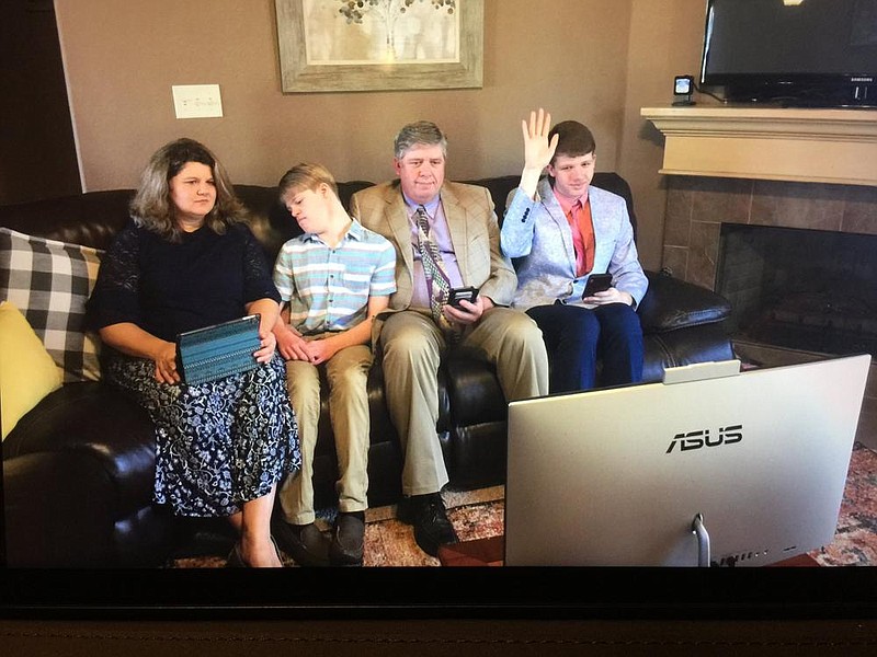 The Hurst family, Sheila (from left), Ezra, Eric and Levi, are seated in front of a computer monitor for virtual Sunday worship with other members of their Jehovah’s Witness congregation. Members of the religion, which is devoted to door-to-door evangelizing, have been practicing their religion virtually since March, when most of its worship houses closed due to the coronavirus pandemic.
(Special to the Democrat-Gazette)