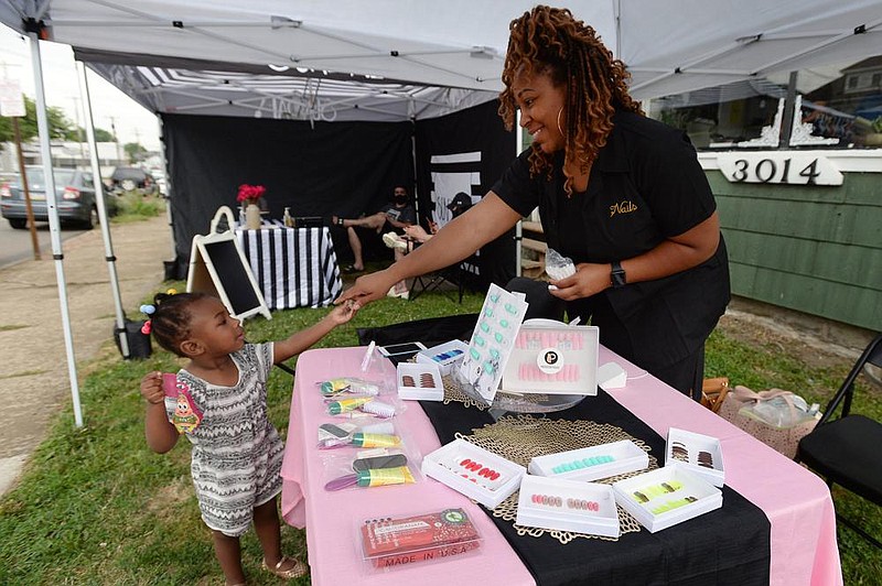 Deanna Dias, owner of Press On Posse, gets some help from her daughter Deena Dias, 2, while selling nail products Saturday during a pop-up shop event at She Vintage in Erie, Pa. (AP/Erie Times-News/Jack Hanrahan) 

