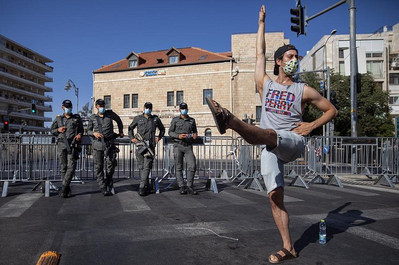 A man dances in front of border police officers Friday during a protest against Israeli Prime Minister Benjamin Netanyahu out- side Netanyahu’s residence in Jerusalem. (AP/Oded Balilty) 