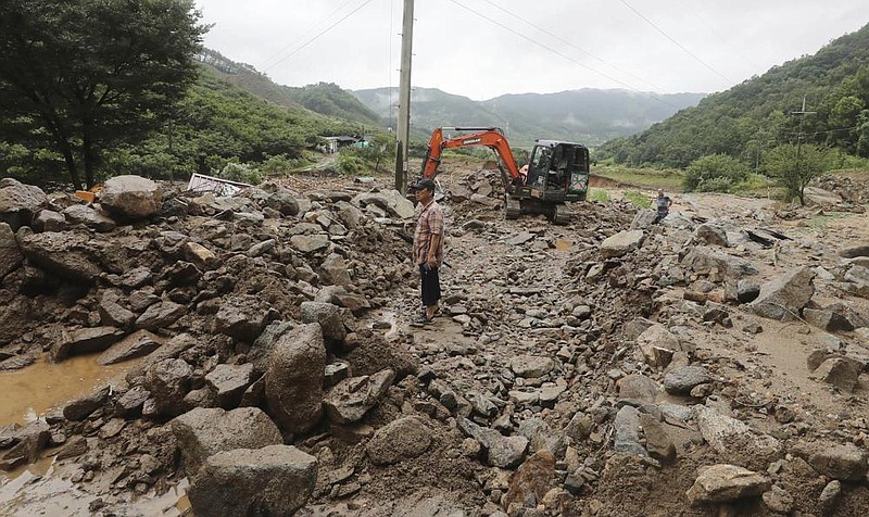 A man stands Sunday on a road covered with mud and rocks after heavy rains in Chungju, South Korea. Video at arkansas online.com/83skorea/ (AP/Yonhap/Chun Kyung-hwan) 
