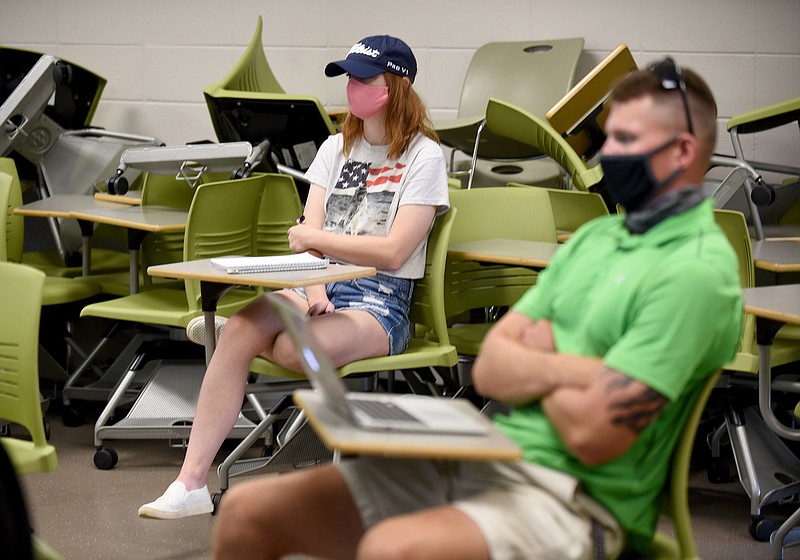 Veronica Hire (left), a senior at the University of Arkansas, and Carter Lanbie, a junior, wear masks and sit distanced from each other as they listen during professor Freddy Dominguez's history course, Wars of Religion, on the first day of a concentrated 10-day course that is part of the University' Intersession term. Students and professors are expected to be wearing masks, and there will be physically-distanced seating in the classrooms on campus in Fayetteville.
