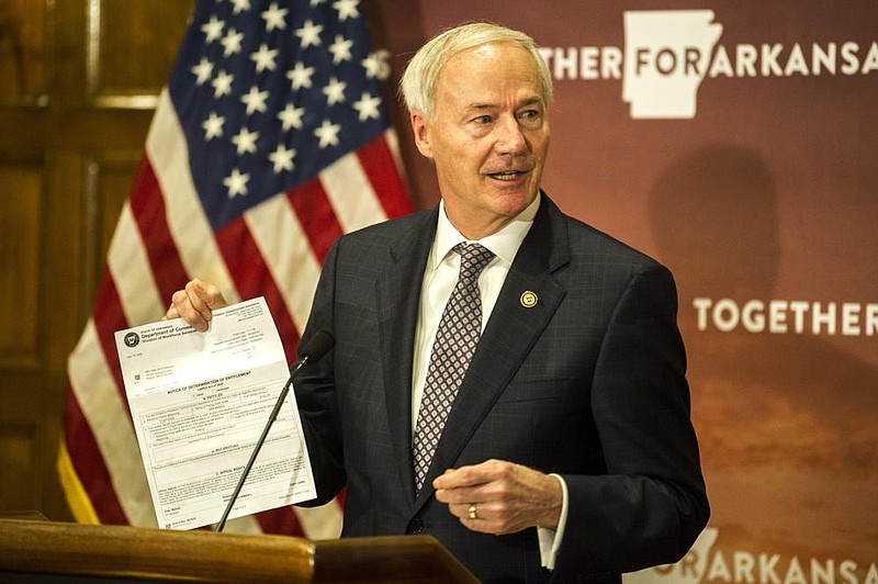 Gov. Asa Hutchinson shows a fraudulent unemployment application — done in his name — during a daily update on Arkansas’ response to covid-19 on Tuesday. More photos at arkansasonline. com/85gov/. (Arkansas Democrat-Gazette/Stephen Swofford) 