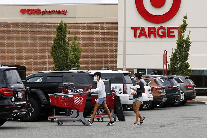 Shoppers take purchases to their vehicle Tuesday at a Target store in Marlborough, Mass. Parents of schoolchildren appear to be holding back on spending because they don’t yet know what the school year will look like in the ongoing pandemic. More photos at arkansasonline.com/laptops/. (AP/Bill Sikes) 