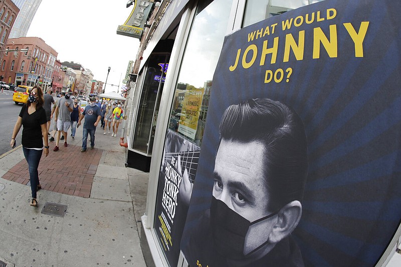 A poster showing music legend Johnny Cash wearing a mask is attached to a storefront in Nashville, Tenn., on Wednesday, Aug. 5, 2020. The wearing of face coverings is required in most public indoor and outdoor situations in Nashville due to an increase of covid-19 cases.
