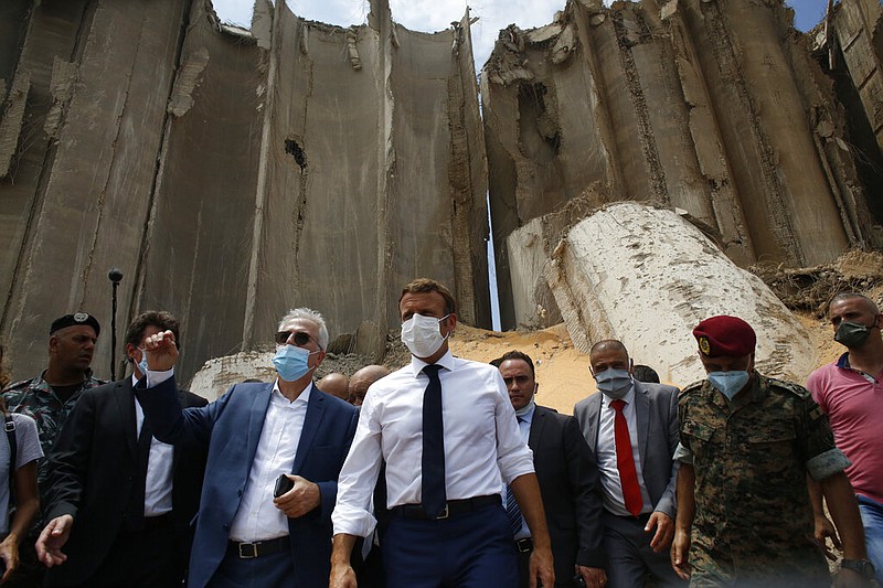 French President Emmanuel Macron, center, visits the devastated site of the explosion at the port of Beirut, Lebanon, Thursday Aug.6, 2020. French President Emmanuel Macron has arrived in Beirut to offer French support to Lebanon after the deadly port blast. (AP Photo/Thibault Camus, Pool)

