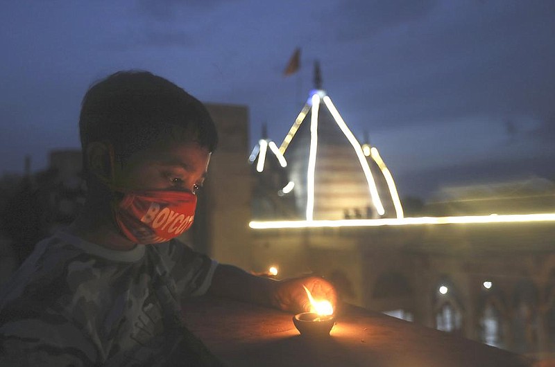 A boy lights an earthen lamp to celebrate the ground breaking Wednesday on a temple dedicated to the Hindu god Ram. The event was conducted by Indian Prime Minister Narendra Modi in New Delhi. The long-awaited temple is at the site of a demolished 16th century mosque. More photos are at arkansasonline.com/86india/.
(AP/Manish Swarup)